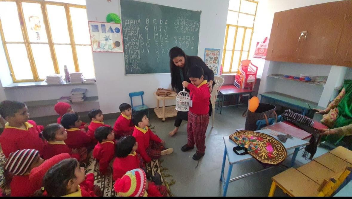 Classroom storytelling with birdcage prop and Hindi chalkboard